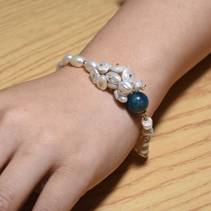 Hand wearing Baroque freshwater pearl bracelet with blue kyanite and gold accents