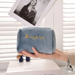 Close-up of blue velvet makeup bag with gold Beautyforyou embroidery and metal zipper