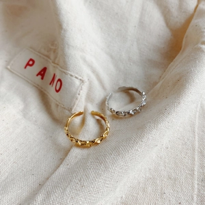 Irregular organic texture open rings in gold and silver finish on soft fabric background