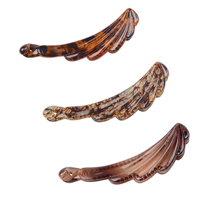 Three feather-shaped banana hair clips in tortoise, spotted, and amber resin finishes