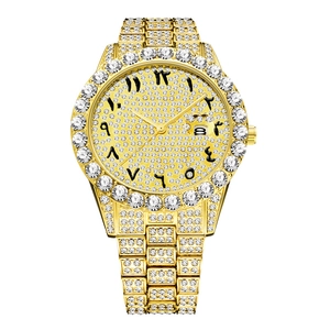 Close-up of gold iced-out watch dial with Arabic numerals and date window detail