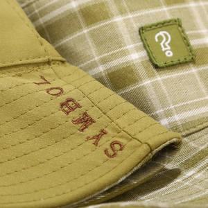 Dettaglio cappello da sole verde con ricamo YORMS e trama in cotone a quadretti