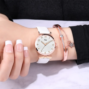 Close-up of elegant ladies' white leather watch set with rose gold bangles on wrist