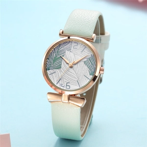 Detail of rose gold watch case with palm leaf dial and mint green leather strap bow