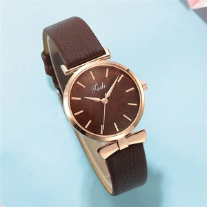 Detailed view of women's watch with rose gold bow link and embossed leaf pattern dial