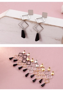 Macro shot of geometric square and diamond earrings with black teardrop pendants