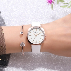 Close-up of thin rose gold watch with white strap and matching heart crystal bracelet