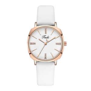 Detailed macro view of minimalist white leather strap and rose gold rhinestone quartz watch