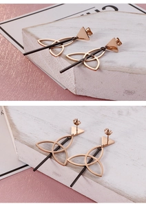 Detail of rose gold Celtic knot earrings with a sleek black bar on a stone block