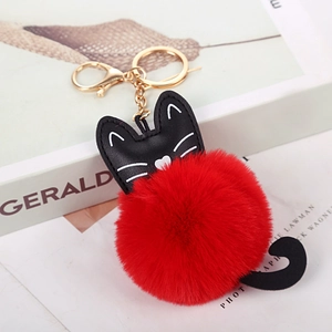 Dettaglio di un portachiavi a gatto nero in PU con pompon rosso in finta pelliccia e anello oro