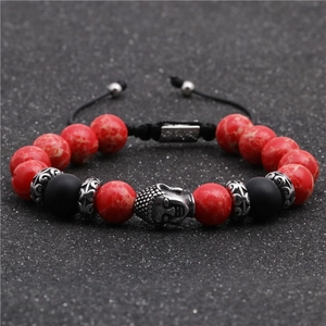 Dettaglio di perle rosse marmorizzate e testa di Buddha in argento su bracciale intrecciato
