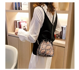 Chic brown snake pattern triangle bag with black handles in a stylish indoor setting
