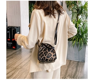 Rear view of a model wearing the leopard print mini crossbody bag with gold hardware