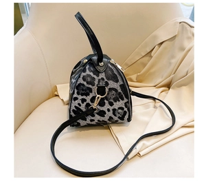 Detail view of mini leopard print bag in black and grey on a beige chair