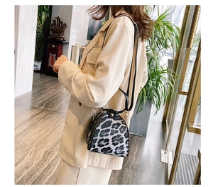 Detail of trendy leopard print triangular handbag with gold hardware and top handle