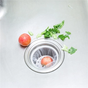 Mesh sink strainer bag capturing food waste in a stainless steel kitchen drain