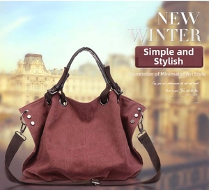 Detail of burgundy canvas tote bag with dark brown straps and silver metal rivet accents