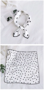 Detail view of a square silk scarf with black heart print and stitched edges
