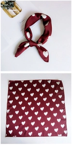 Detail of wine red square silk scarf featuring a white heart pattern and satin finish
