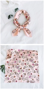 Detailed pattern of light pink silk scarf with heart, poker, and envelope prints