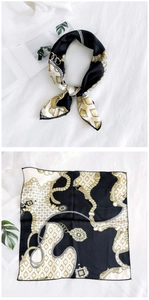 Detailed view of square silk scarf with gold chain patterns and smooth satin finish