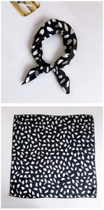 Close-up of black floral square silk scarf showing dense hem edge and knotted styling