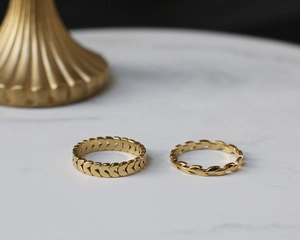 Detailed macro view of 18K gold plated wheat ear and heart patterns on steel rings