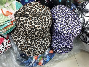 Close-up showing various printed patterns on canvas bucket hats including leopard and palms