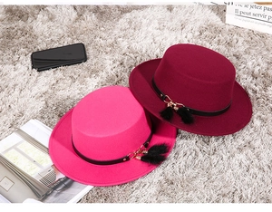 Detailed shot of rose red and burgundy flat top wool hats with decorative leather straps
