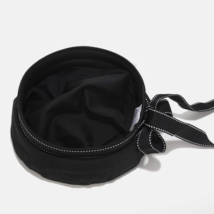 Black beret hat with a decorative white-edged ribbon bow and embroidered letters detail