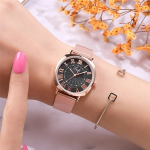 Elegant rose gold women's watch with black Roman dial and mesh strap on a model's wrist