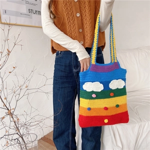 Rainbow crochet tote bag with white cloud decor shown in a stylish model lifestyle shot