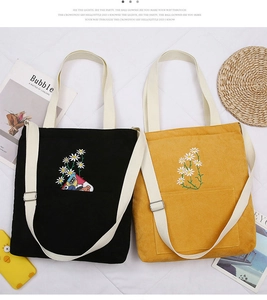 Detail of corduroy shoulder bags with daisy embroidery in black and mustard yellow colors
