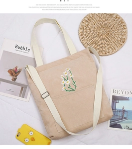 Detailed view of beige corduroy tote bag with white daisy embroidery and adjustable strap