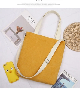Detail of yellow corduroy tote bag with daisy embroidery and adjustable strap in flat lay