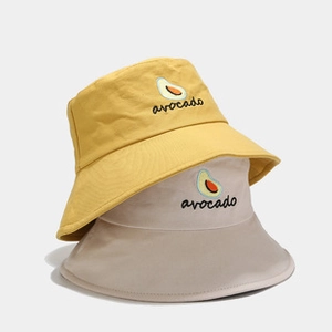 Dettaglio del ricamo avocado su cappelli bucket in cotone nei colori giallo e beige