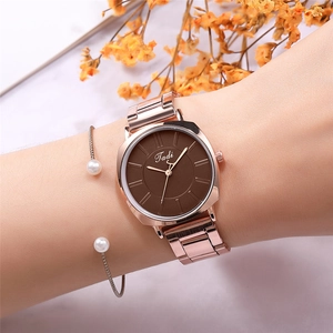 Detail shot of rose gold alloy watch with brown dial and matching pearl bracelet on wrist
