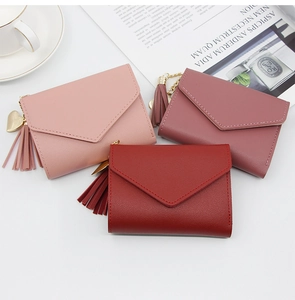 Detail of envelope-style leather wallets in three pink shades with tassel and heart charm