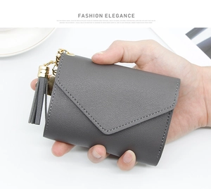 Detail of dark grey lychee leather wallet with elegant gold tassel and key ring clip