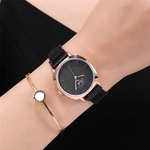 Détail d'une montre à quartz noire avec bracelet milanais or rose et bracelet doré assorti