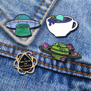 Detailed view of four creative cartoon enamel pins on blue denim fabric background