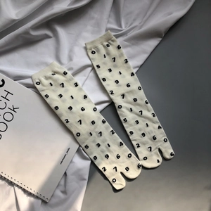 Detail of tabi socks with black number print on cream knit fabric in a minimalist setting