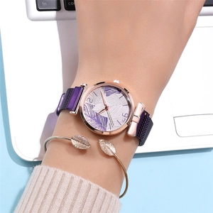 Close-up of rose gold watch with purple leaf dial and matching gold leaf bangle