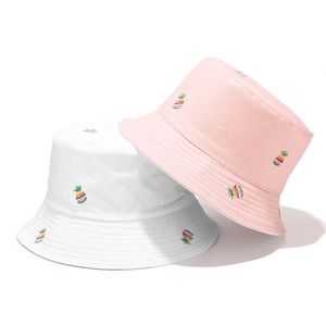 Detail of white and pink bucket hats featuring colorful pineapple embroidery patterns