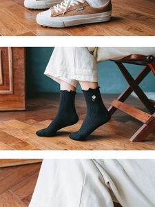 Detail of black frilly crew socks featuring daisy embroidery and lettuce trim edges