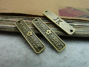 Macro shot of rectangular bronze handmade metal charms with dual holes for jewelry making