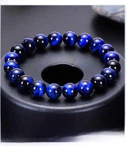 Macro shot of natural blue tiger eye stone bracelet with smooth polished beads on black base