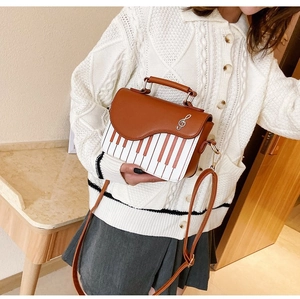 Detail of piano-themed handbag with wavy flap and musical note pendant decoration