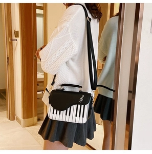 Detail view of piano keyboard pattern bag with silver treble clef logo on a fashion model