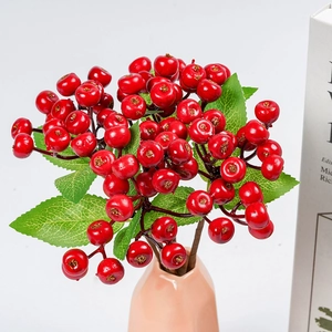 Artificial red berries branch in a pink vase with home decor books on a warm table
